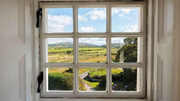 Ein Fenster mit Blick auf ein Feld und eine Straße