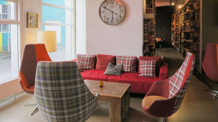Ein Wohnzimmer mit einer Couch und Stühlen und einer Uhr an der Wand
