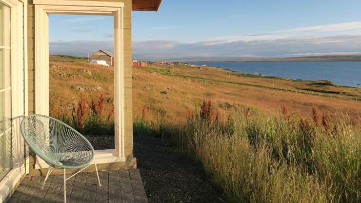 Ein blauer Stuhl sitzt auf einem Balkon mit Blick auf das Meer