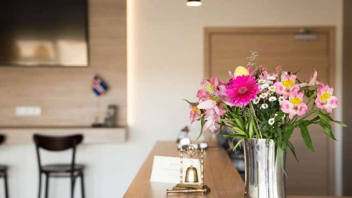 Eine Vase mit Blumen sitzt auf einem Holztisch