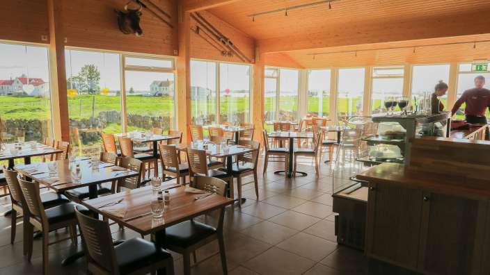 Ein Restaurant mit vielen Tischen und Stühlen und vielen Fenstern