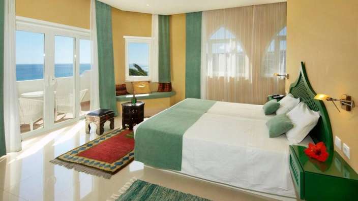 Ein Schlafzimmer mit einem Bett und einem Fenster mit Blick auf das Meer