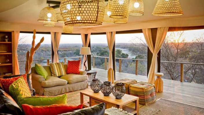 Ein Wohnzimmer mit vielen Möbeln und einem Balkon mit Blick auf einen Fluss