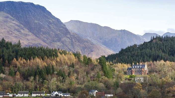 Ein großes Gebäude sitzt auf einem Hügel inmitten eines Waldes