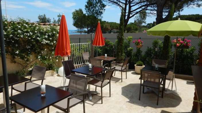 Eine Terrasse mit Tischen und Stühlen und Regenschirmen