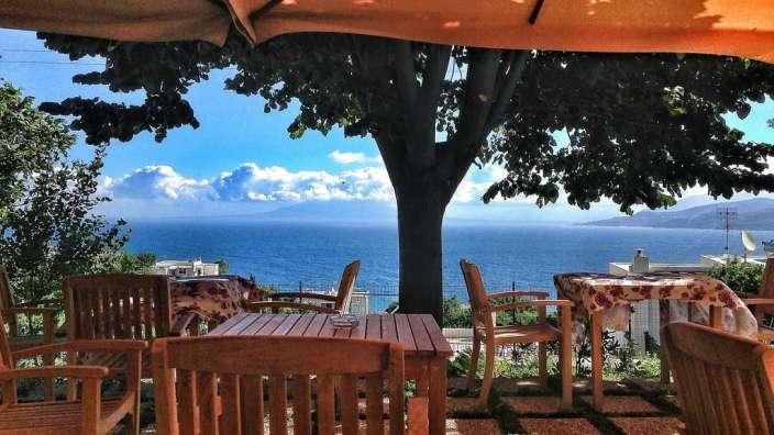 Ein Tisch und Stühle unter einem Sonnenschirm mit Blick auf das Meer