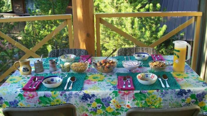 Ein Tisch mit einer bunten Blumendecke und vielen Schüsseln mit Essen darauf
