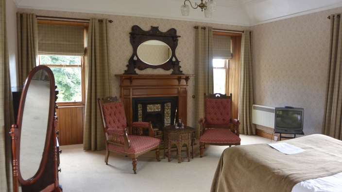 Ein Schlafzimmer mit zwei Stühlen und einem Kamin