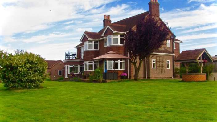 Ein großes Backsteinhaus mit einem großen Rasen vorne