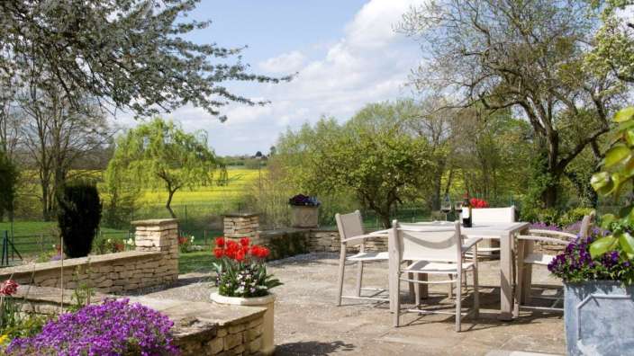 Eine Terrasse mit einem Tisch und Stühlen und lila Blumen