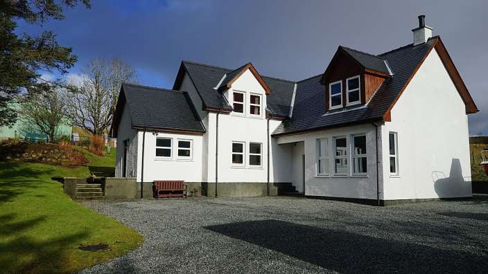 Ein weißes Haus mit einem schwarzen Dach und vielen Fenstern