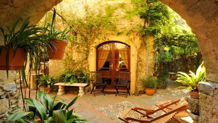 Eine Terrasse mit Schaukelstühlen und Stühlen vor einem gelben Gebäude