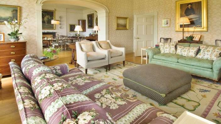 Ein Wohnzimmer mit lila und grünen Möbeln und einem Ottoman