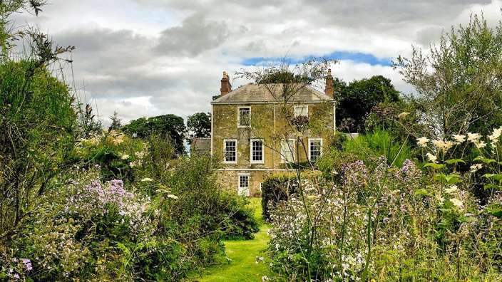 Ein großes Haus mit vielen Bäumen und Blumen davor