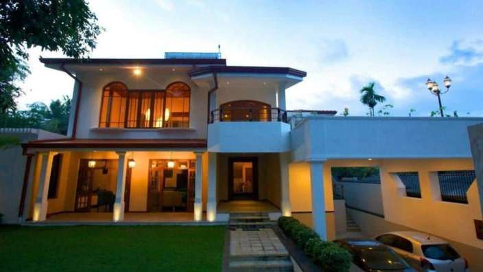 Ein großes weißes Haus mit zwei Autos vorne geparkt