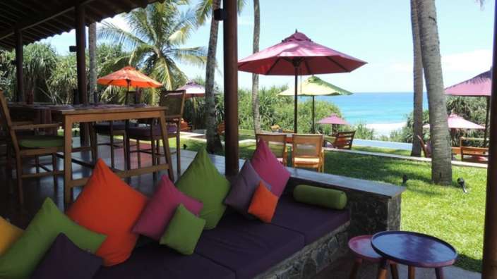 Eine Terrasse mit bunten Kissen und Regenschirmen mit Blick auf den Ozean