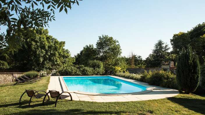 Ein großer Swimmingpool umgeben von Stühlen und Bäumen