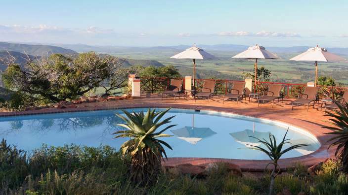 Ein großer Pool mit Liegestühlen und Sonnenschirmen umgeben