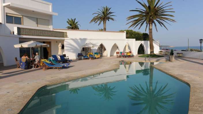 Eine Gruppe von Menschen sitzt an einem Tisch in der Nähe eines Swimmingpools