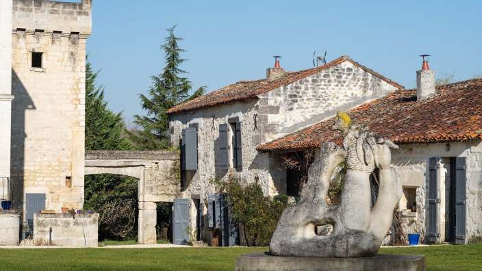 Eine Statue einer Hand steht vor einem Steingebäude