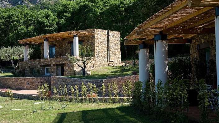 Ein Steinhaus mit einem Holzdach und weißen Säulen