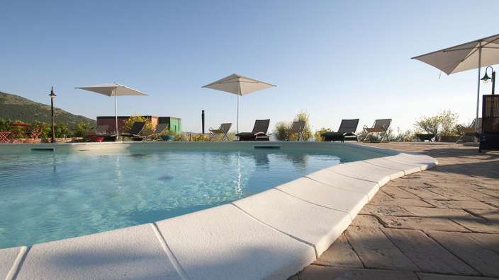 Ein großer Pool mit Liegestühlen und Sonnenschirmen um ihn