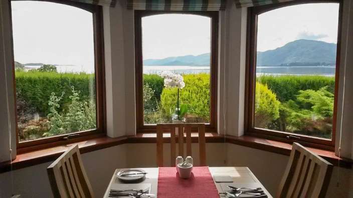 Ein Tisch und Stühle in einem Esszimmer mit Blick auf einen See