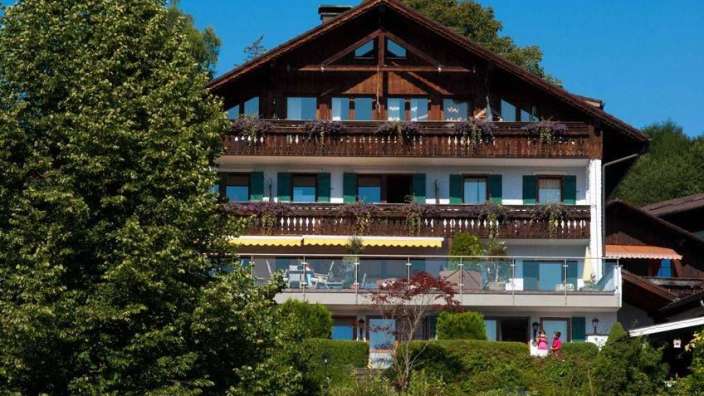 Eine Gruppe von Menschen steht auf einem Balkon vor einem großen Holzhaus