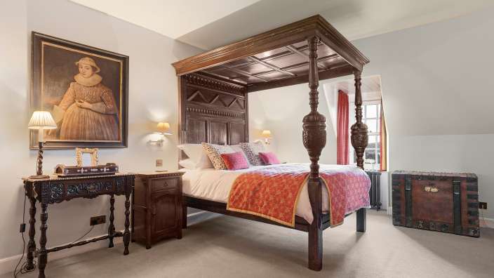 Ein Schlafzimmer mit einem Himmelbett und einem Gemälde an der Wand