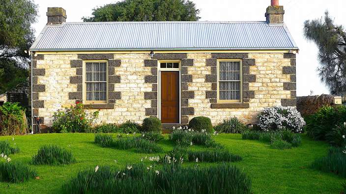 Ein kleines Steinhaus mit einem Metalldach und einer braunen Tür
