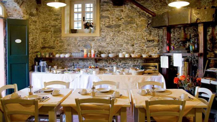 Tische und Stühle in einem Speisesaal mit einer Steinmauer