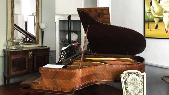 Ein Klavier steht in einem Raum mit einem Spiegel und einem Gemälde an der Wand