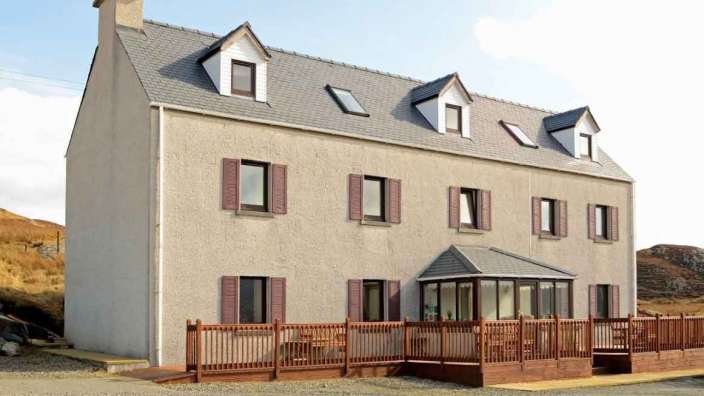 Ein großes Haus mit vielen Fenstern und einem Holzdeck