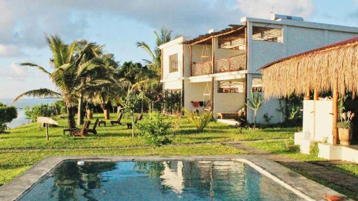 Ein großer Pool in der Nähe eines Hauses mit Strohdach