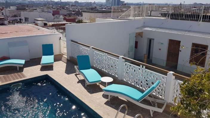 Liegestühle stehen neben einem Swimmingpool mit Blick auf die Stadt