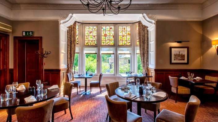 Ein Esszimmer mit Tischen und Stühlen und einem Buntglasfenster