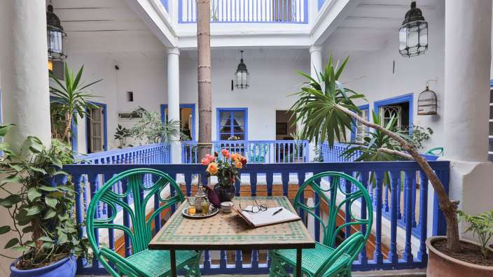 Ein blau-weißer Balkon mit einem Tisch und Stühlen