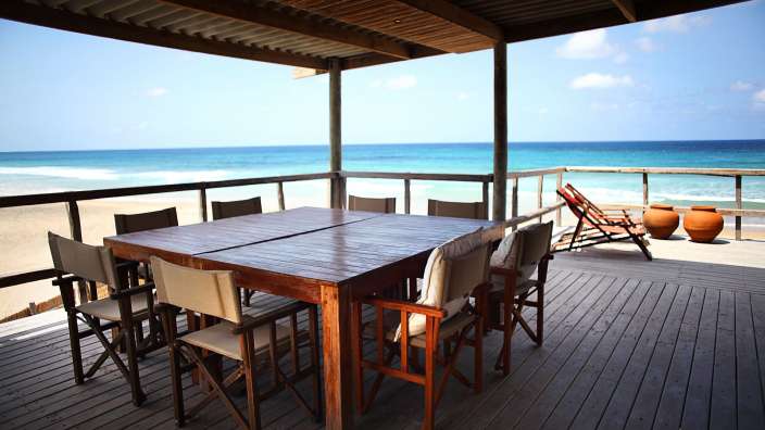 Ein Tisch und Stühle auf einem Deck mit Blick auf den Ozean