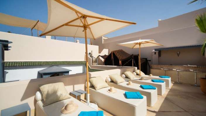 Eine Terrasse mit Liegestühlen und Sonnenschirmen und blauen Handtüchern