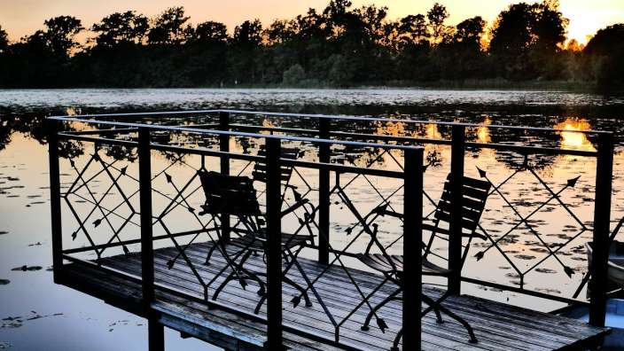 Ein Dock mit Stühlen und einem Tisch auf einem See bei Sonnenuntergang