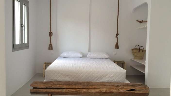 Ein weißes Schlafzimmer mit einem Bett und einer Holzbank