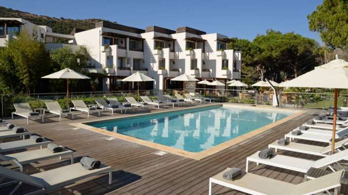Liegestühle und Sonnenschirme umgeben einen großen Swimmingpool