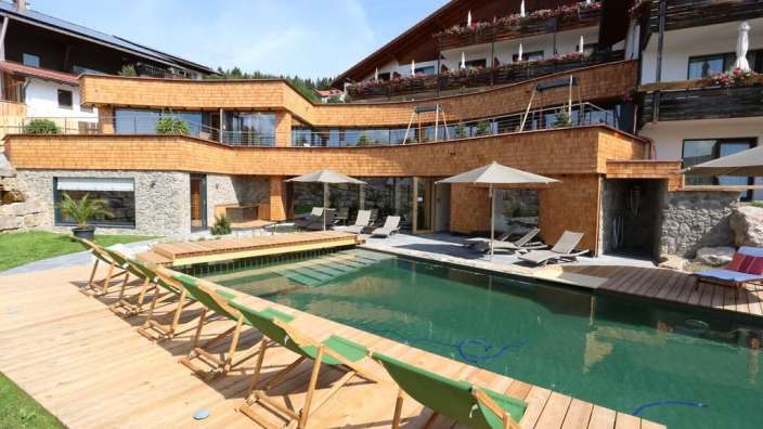 Liegestühle und Sonnenschirme stehen neben einem großen Swimmingpool