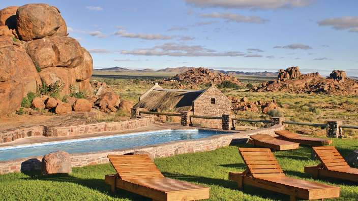 Liegestühle neben einem Swimmingpool mit einem Steingebäude im Hintergrund