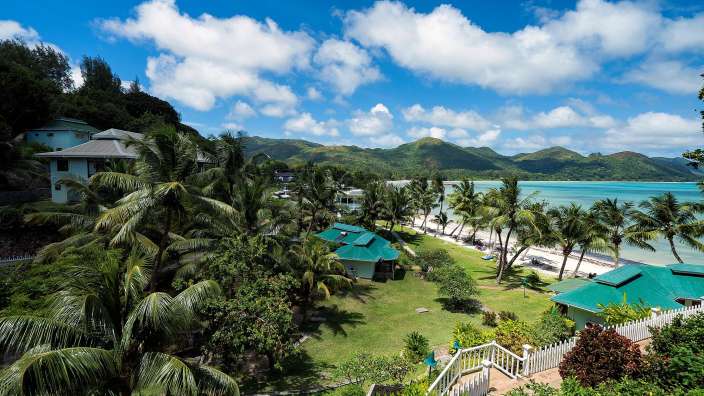 Blick auf einen tropischen Strand mit Bäumen und Häusern