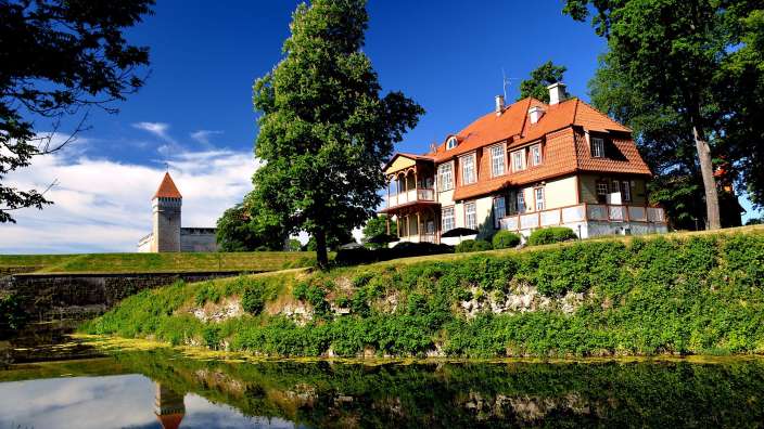 Ein Haus mit einem roten Dach sitzt neben einem Teich