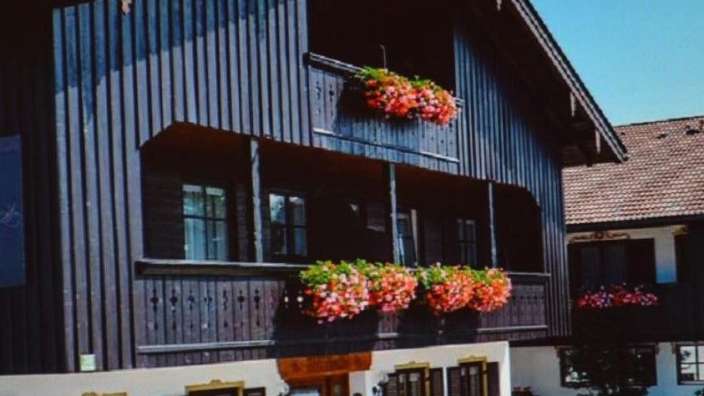 Ein braunes Haus mit einem Balkon und Blumen darauf