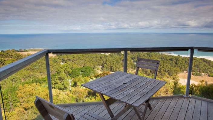 Ein Tisch und Stühle auf einem Balkon mit Blick auf das Meer