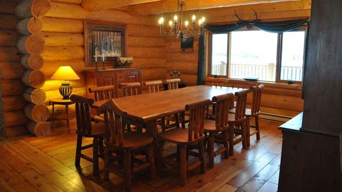 Ein Esszimmer in einem Blockhaus mit einem Tisch und Stühlen