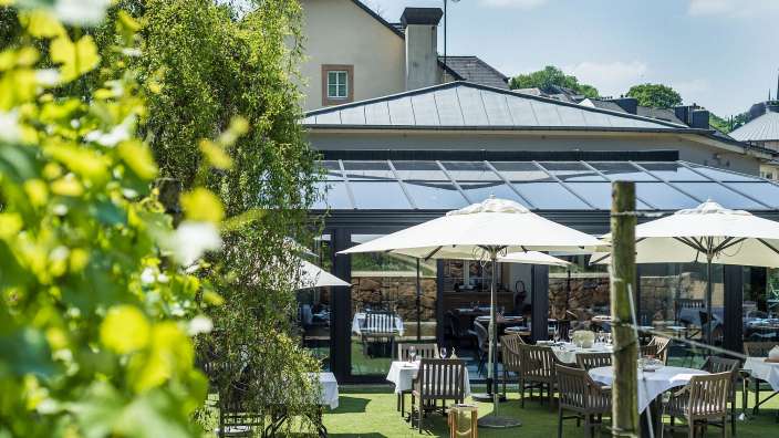 Eine Terrasse mit Tisch und Stühlen und Sonnenschirmen vor einem Gebäude